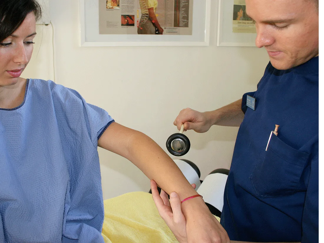 Chiropractor testing reflexes at a patient’s elbow