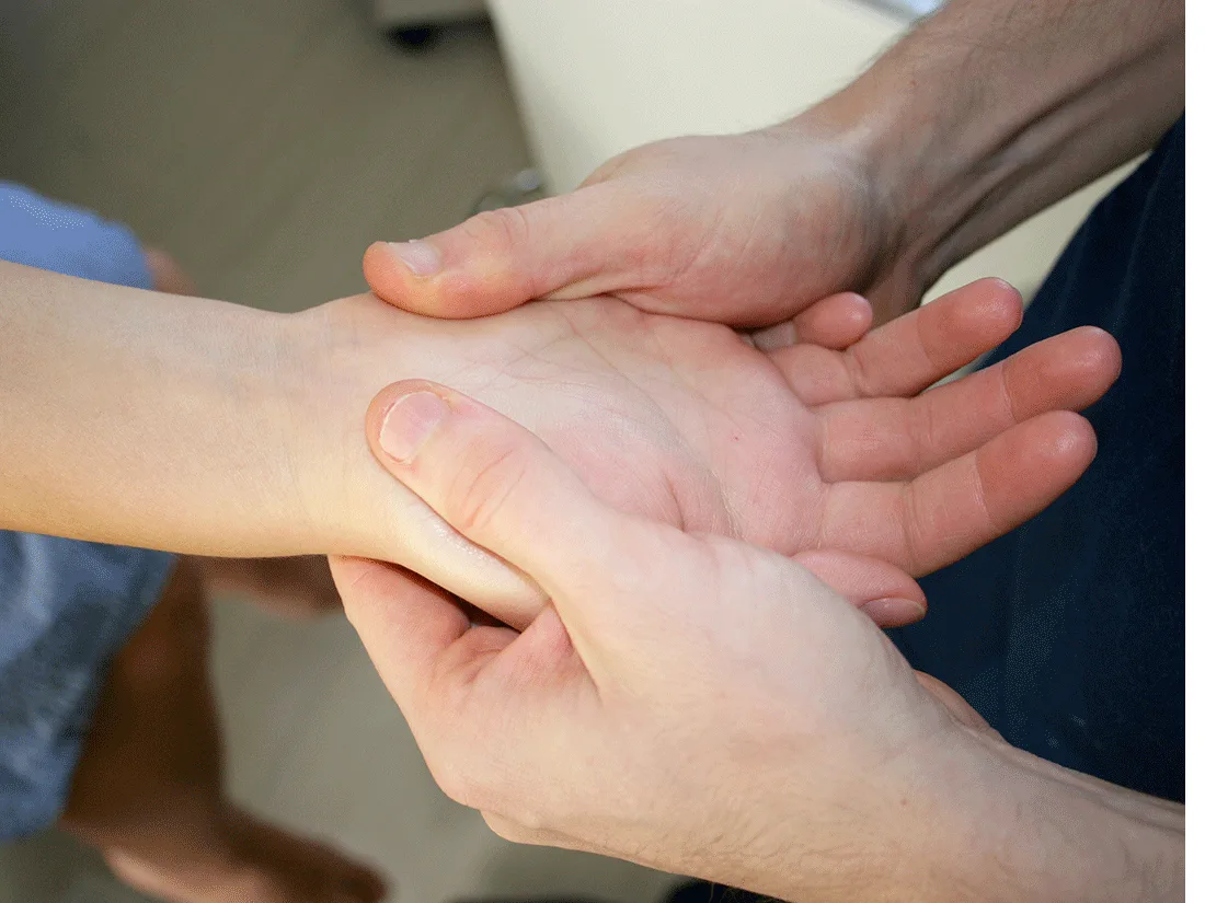 Chiropractor’s hands examining a patient’s wrist and palm